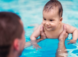 Smilling baby boy in swimming pool A one year old is smiling in a pool while being held up in the water by a swim instructor