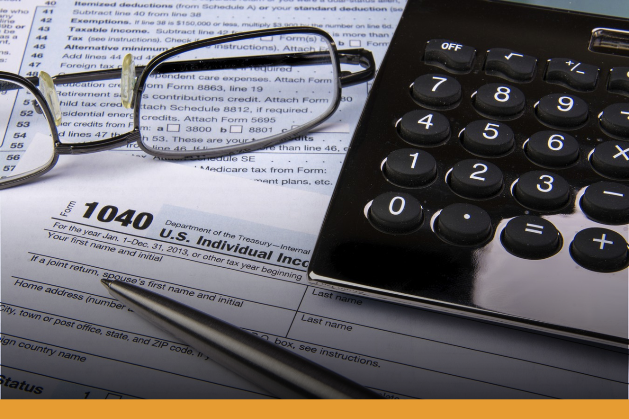 Accountancy Reading glasses, calculator, pen on top of tax forms
