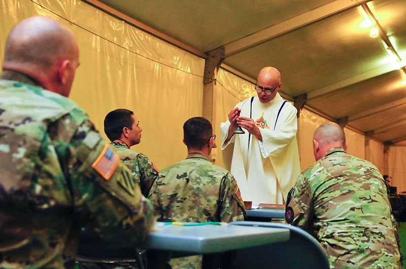 Maj. Patrick Brownell, Brigade Chaplain for the 230th Sustainment Brigade, Tennessee Army National Guard, administers a Catholic service to Soldiers training at the National Training Center, Fort Irwin, Calif. on May 6. 