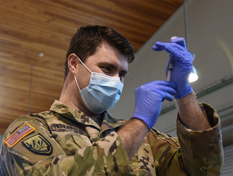 Soldier using a syringe with doses of the COVID-19 vaccine