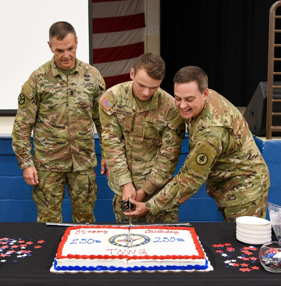 Tennessee's Senior Enlisted Leader, Command Sgt. Maj. Dale Crockett, watches as Pfc. Christian Amacher and Col. Mark Phillips cut the ceremonial cake during the Tennessee National Guard's 250th birthday celebration Aug. 16 at Joint Force Headquarters in Nashville. (Photo by Retired Sergeant 1st Class Edgar Castro)