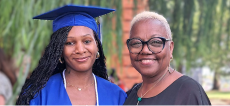 Adult Education Woman wearing a mortarboard and graduation gown stands next to other woman