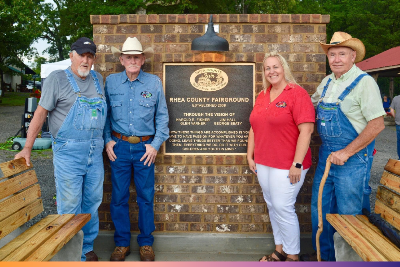 George Beaty, Jim Hall, Brittany Fisher Dean and Glen Varner stand in front of a plaque at the Rhea County Fairgrounds
