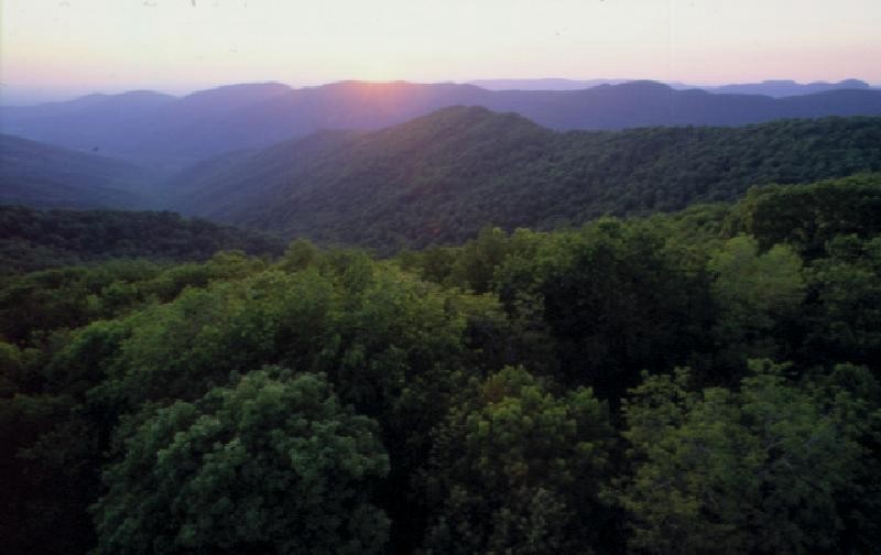 A sunset over forested hills