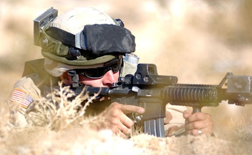 A Tennessee Army National Guard Soldier in full tactical gear, laying in a field, aiming a rifle. A Tennessee Army National Guard Soldier in full tactical gear, laying in a field, aiming a rifle.
